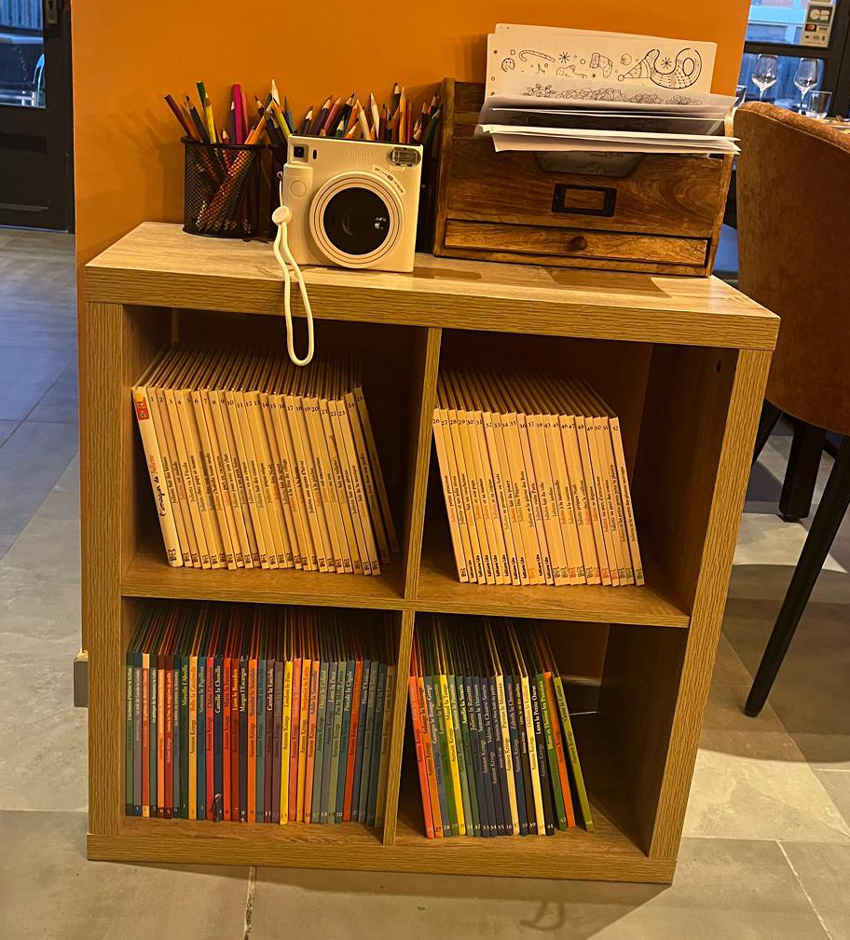 Petite étagère remplie de livres et de crayons pour les enfants au Resturant l'Empreinte